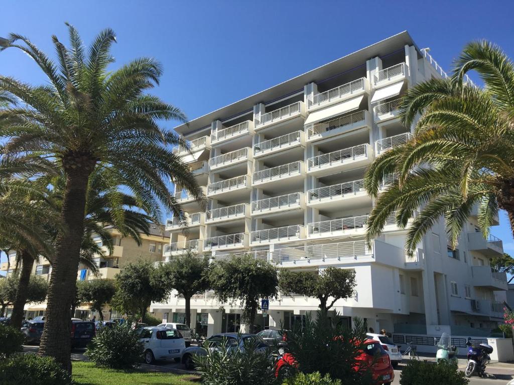 un grand immeuble d'appartements blanc avec des palmiers dans l'établissement FRONTE MARE-CENTRALE-Riviera Palace-Giulianova-Apartment-nei mesi di Luglio e Agosto Prenotazioni solo da Sabato a Sabato, à Giulianova