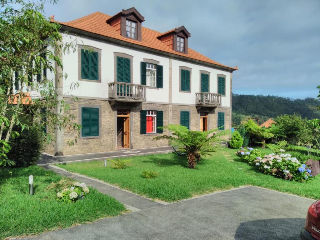 uma casa grande com persianas verdes e um quintal em Quinta do Serrado em Porto Moniz