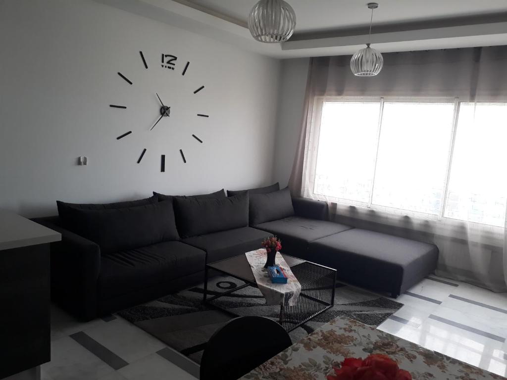 a living room with a couch and a clock on the wall at Harmony Appartement 12 in Tunis