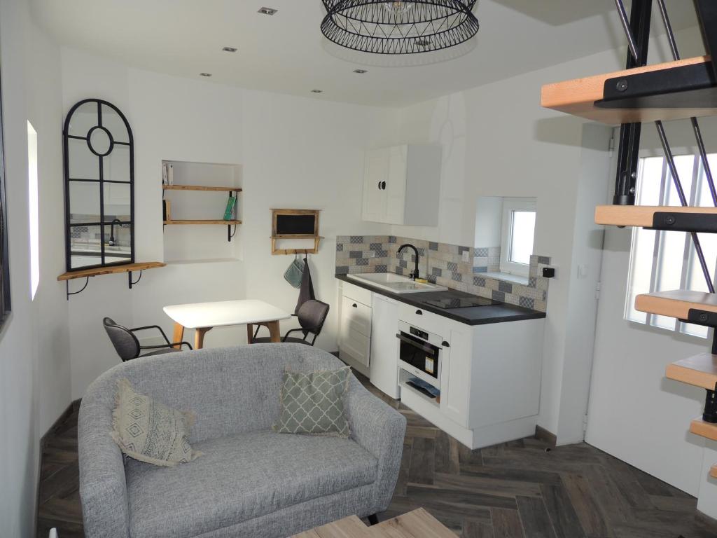 ein Wohnzimmer mit einem Sofa und einer Küche in der Unterkunft Appartements du 101 in Villeneuve d'Ascq