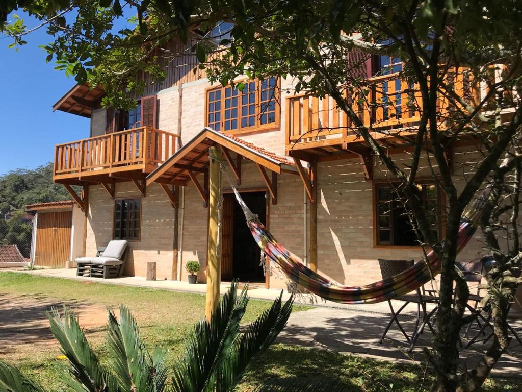 une maison avec un hamac en face de celle-ci dans l'établissement Chalé da Bel, à Santo Antônio do Pinhal