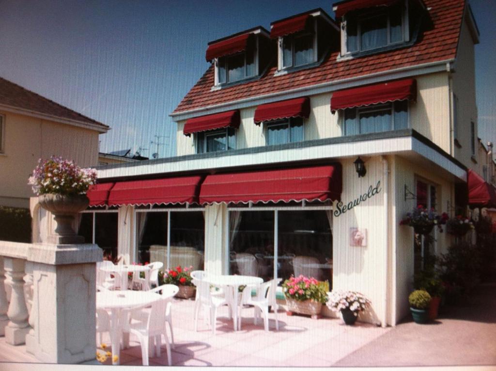 un restaurante con mesas y sillas blancas frente a un edificio en Seawold Guest House, en St Brelade