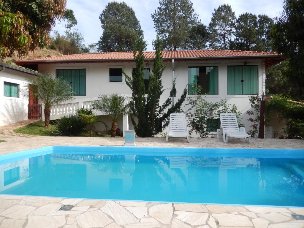 uma casa com piscina em frente a uma casa em Chácara do Delei em São Luiz do Paraitinga