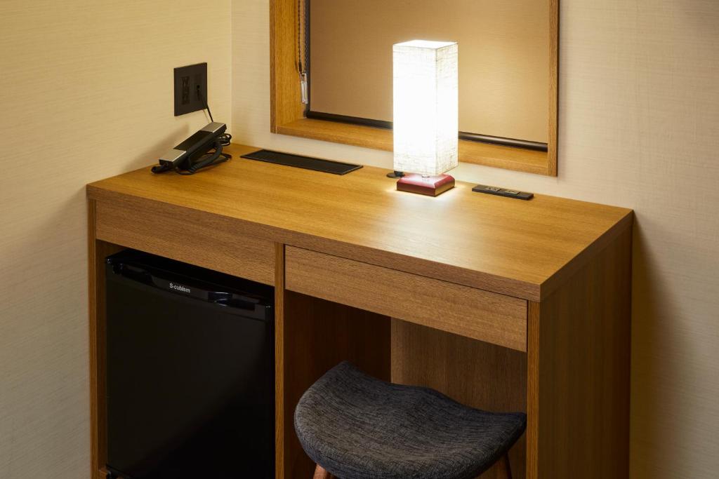 a desk in a hotel room with a lamp and a chair at Rinn Gion Kenninji in Kyoto
