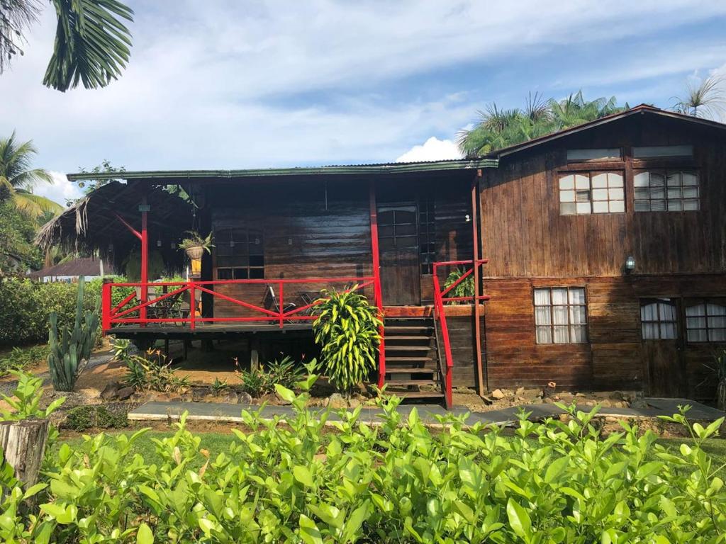 drewniany dom z czerwonymi schodami przed nim w obiekcie Posada turística Quenari Wii w mieście Mitú