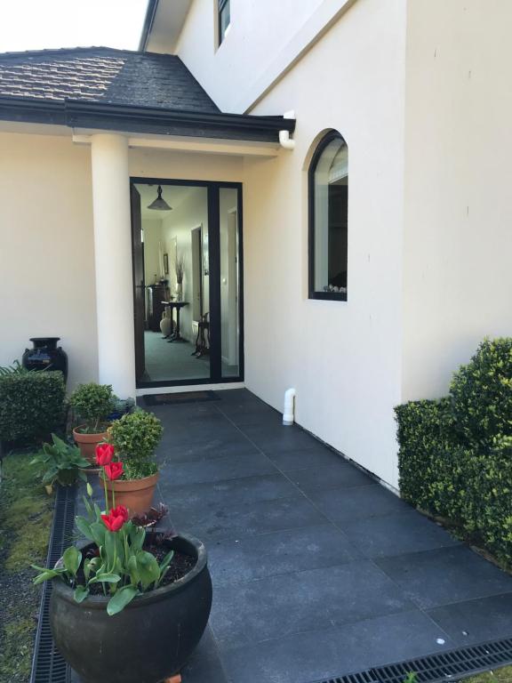 a porch of a white house with pots of flowers at Apartment 45 @ Noble Estate in Waikanae