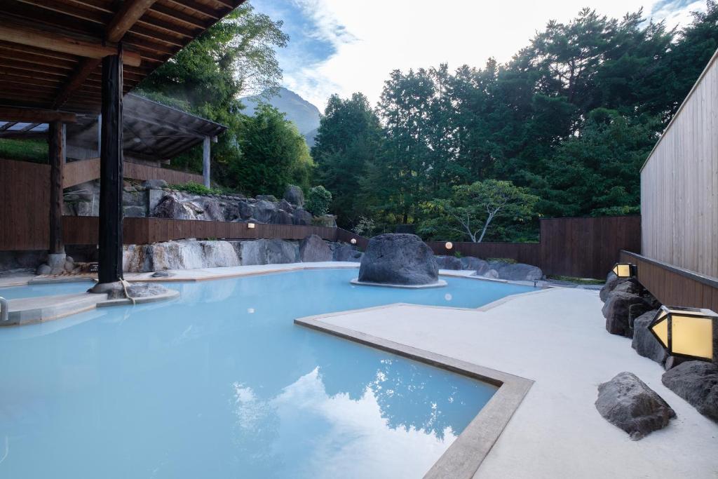 uma piscina com água azul num jardim zoológico em Yufuin Onsen Tsukanoma em Yufu
