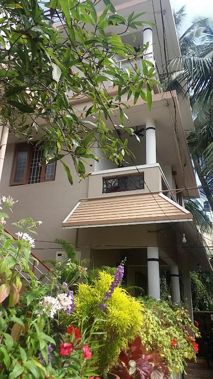 un edificio con balcón y flores delante de él en kevins Placid Homestay, en Kochi