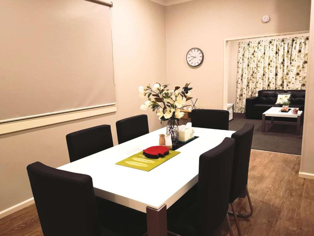 comedor con mesa blanca y sillas negras en Home Sweet Home, en Oamaru