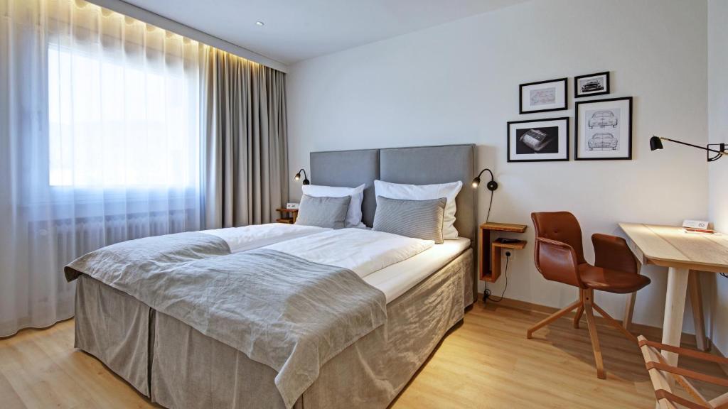 ein Schlafzimmer mit einem großen Bett, einem Schreibtisch und einem Stuhl in der Unterkunft Hotel am Engelberg in Winterbach