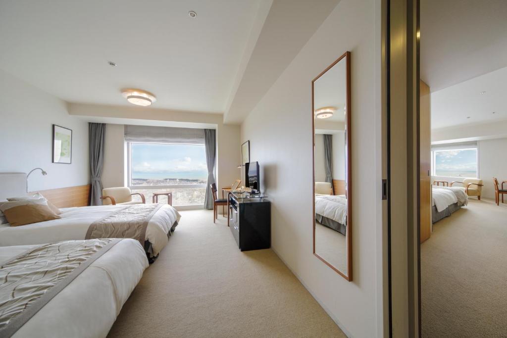 a hotel room with two beds and a mirror at Hotel Nikko Niigata in Niigata