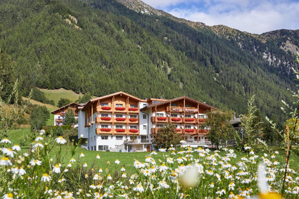a hotel in the mountains with a field of flowers at Alpenhotel Schönwald Superior in Valles