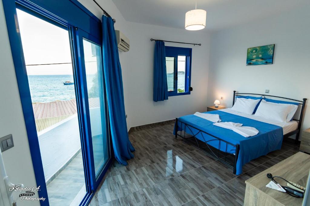 a bedroom with a blue bed with a view of the ocean at Riva Del Mare in Archangelos