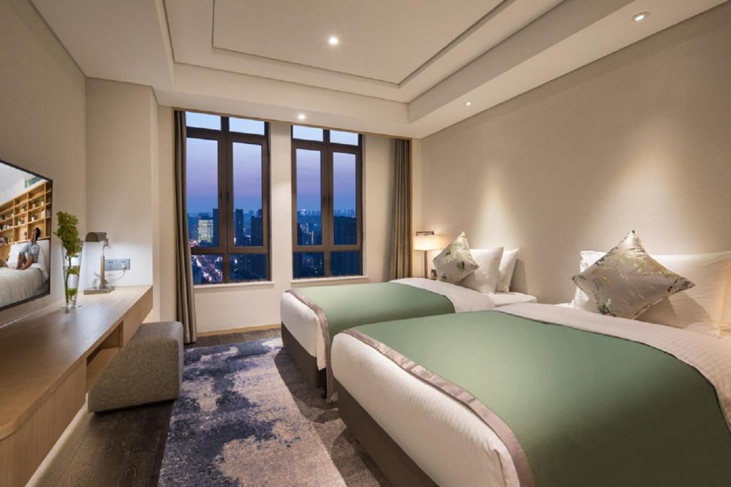 a hotel room with two beds and a television at Somerset Harmony City Wuxi in Wuxi