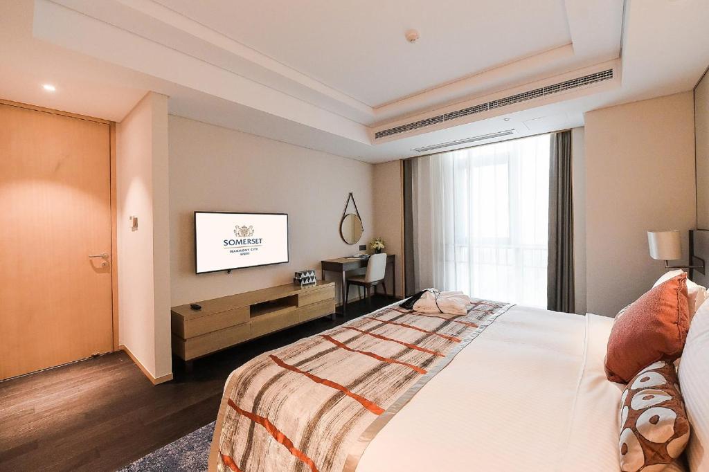 a hotel room with a bed and a television at Somerset Harmony City Wuxi in Wuxi