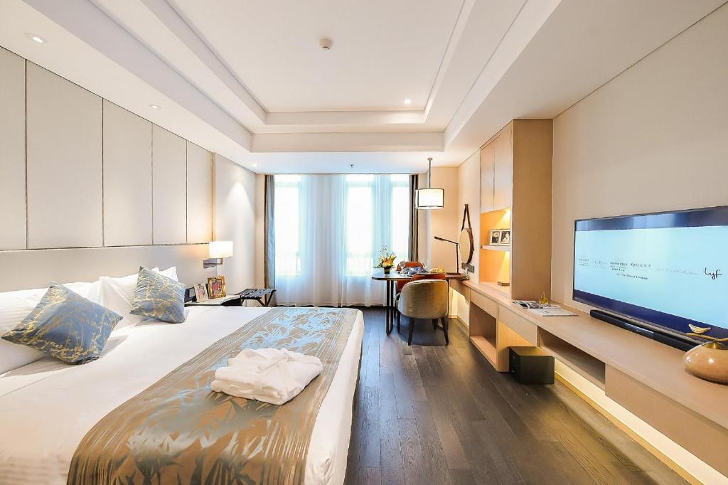 a hotel room with a large bed and a flat screen tv at Somerset Harmony City Wuxi in Wuxi