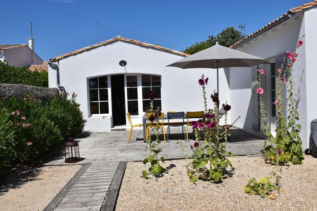 a white house with an umbrella and some flowers at Villa Blanche in Loix