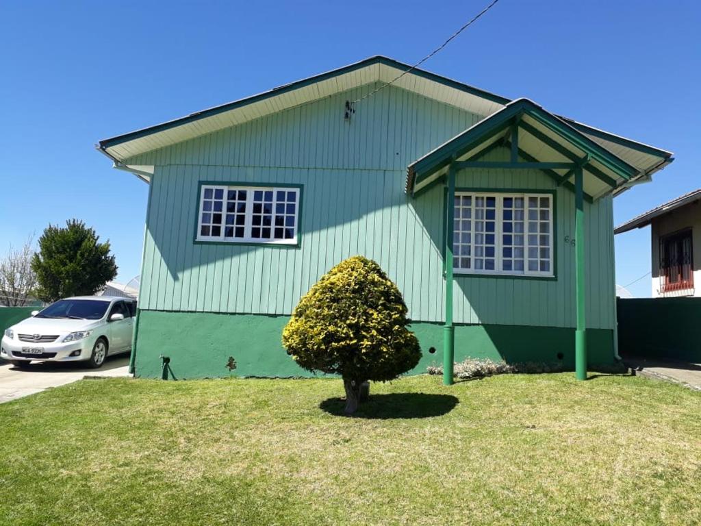 una casa verde con un árbol delante en Pousada Cravo e Canela SJ en São Joaquim