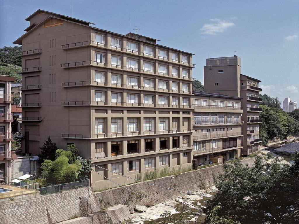 ein hohes Gebäude neben einem Fluss mit Gebäuden in der Unterkunft Itoen Hotel Iizakakanouya in Fukushima
