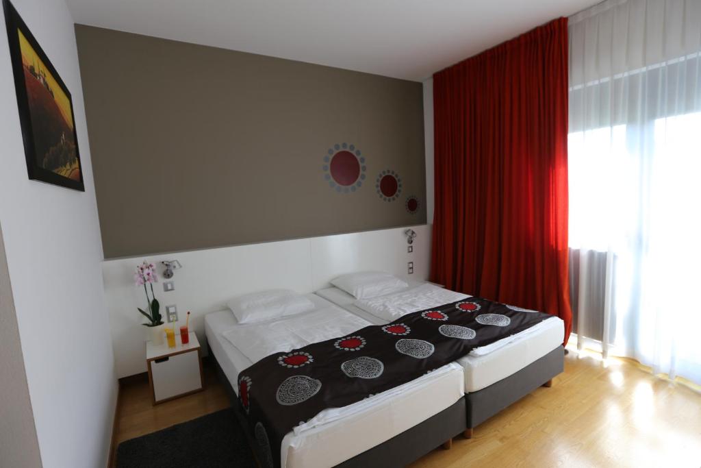 a bedroom with a bed with a red curtain at Hotel Draganic in Draganići