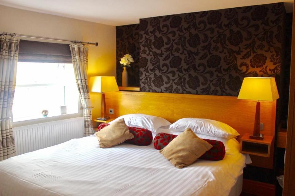 sypialnia z białym łóżkiem z poduszkami i oknem w obiekcie The Groves Inn w mieście Knaresborough
