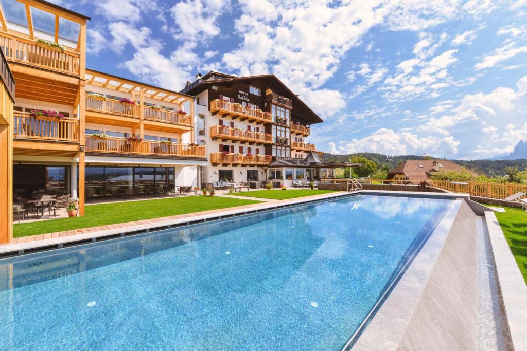 a resort with a swimming pool in front of a building at Hotel Regina in Soprabolzano