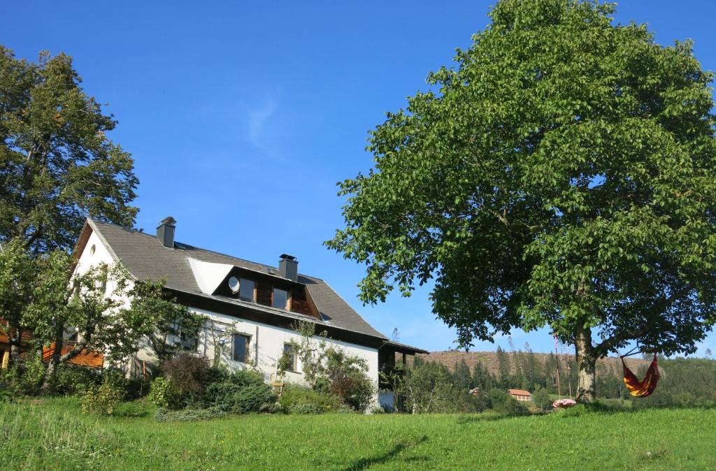 Ein weißes Haus auf einem Feld mit einem Baum in der Unterkunft Urlaub wie früher bei Oma in Hermagor