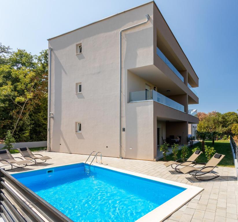 ein Haus mit einem Swimmingpool vor einem Gebäude in der Unterkunft Villa Neda in Malinska