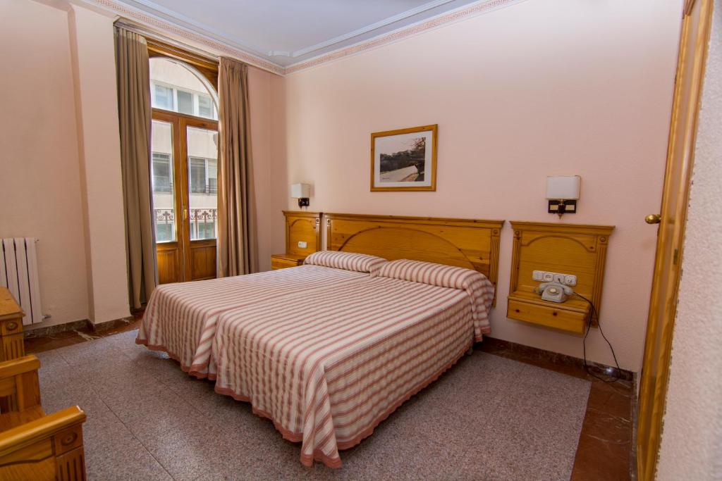 1 dormitorio con 1 cama con manta a rayas en Hotel Europa, en Albacete