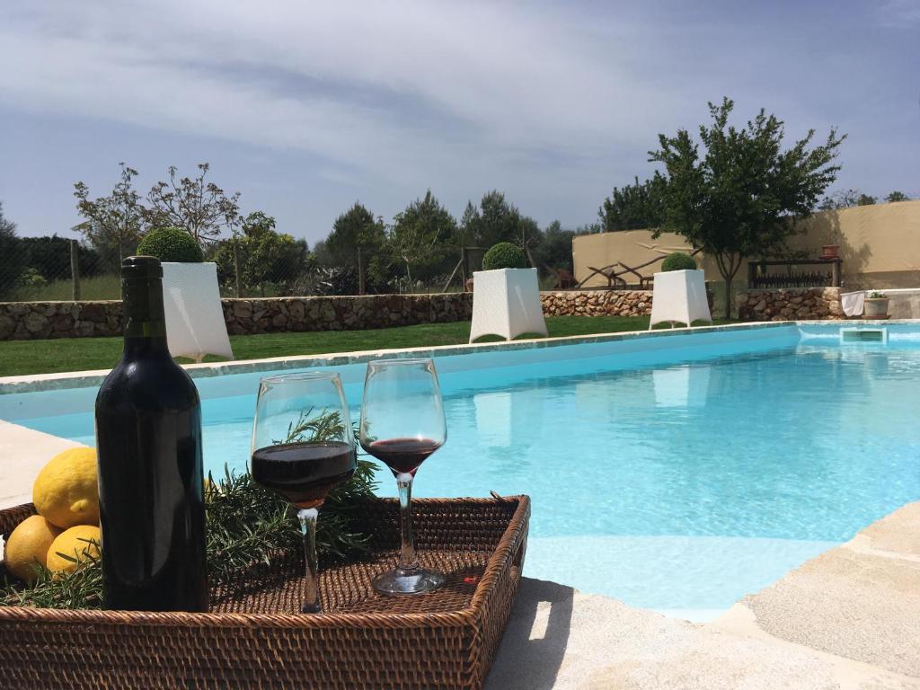 a bottle of wine and two glasses next to a swimming pool at Sa Estada in Sineu