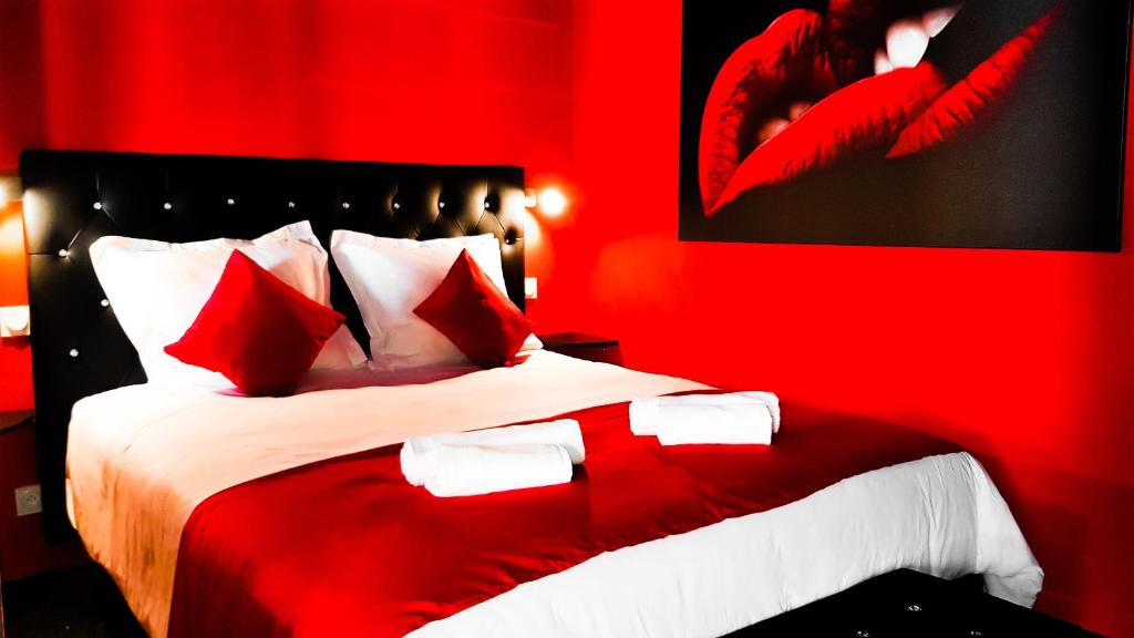 a red bedroom with a large bed with red pillows at Suite Romantique in Narbonne