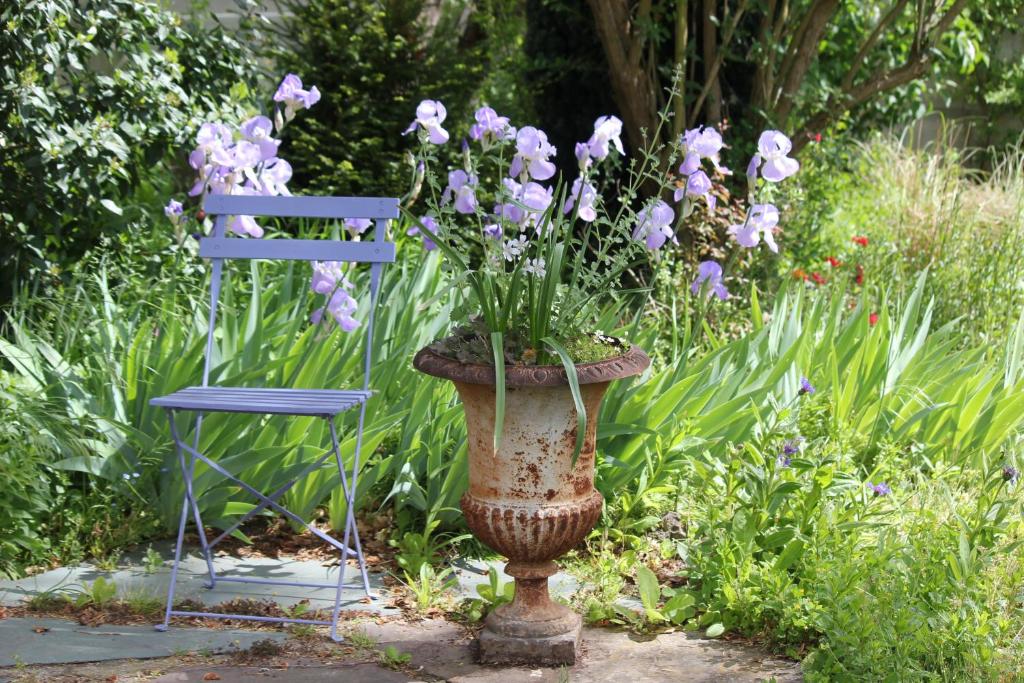 un jarrón lleno de flores púrpuras junto a una silla azul en Le Chemin du Village en Croth