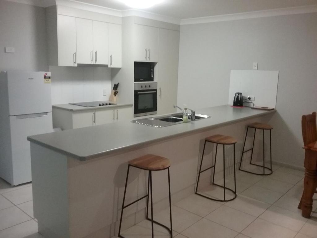 a kitchen with a counter and stools in it at Banksia and Acacia Apartments in Maryborough