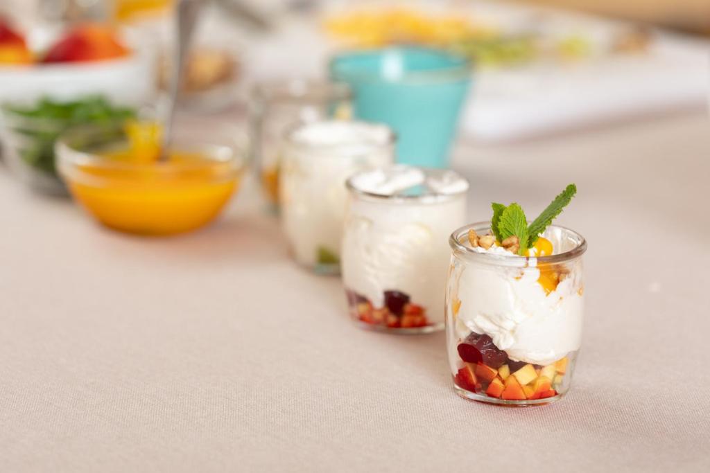 a row of small jars filled with fruit and whipped cream at Unirea Hotel & Spa in Iaşi