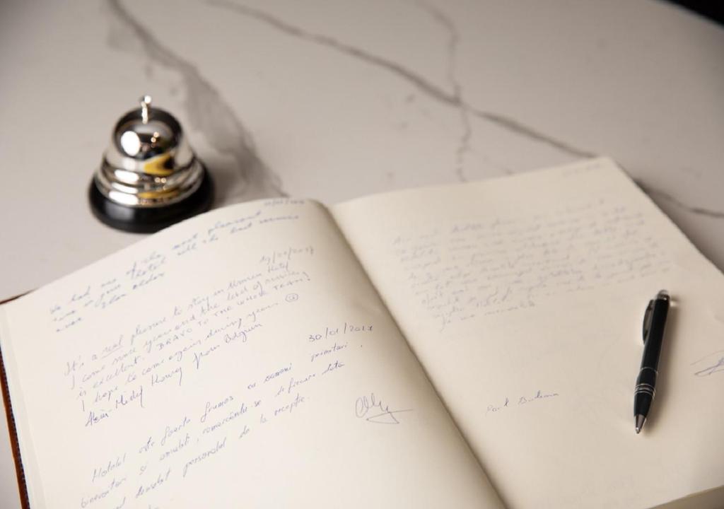 an open book with a pen on a table at Unirea Hotel & Spa in Iaşi