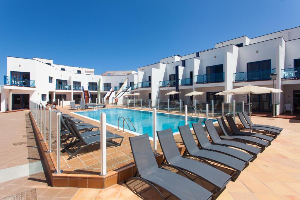 a row of lounge chairs next to a swimming pool at TAO El Cotillo in El Cotillo