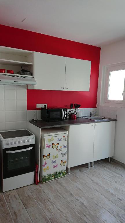 une cuisine avec des placards blancs et un mur rouge dans l'établissement Studio, à Auch