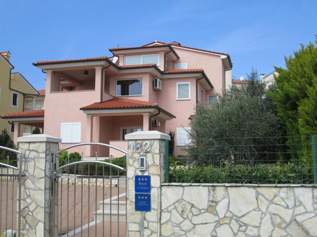 una casa rosa con una puerta y una valla en Apartments Villa Fernetich, en Premantura