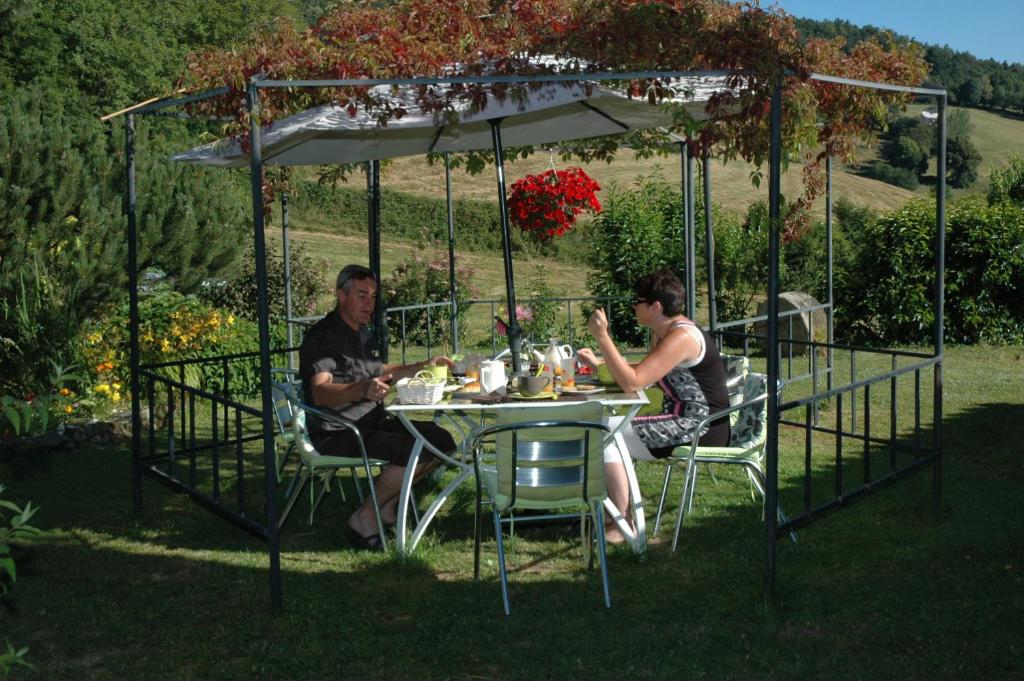 a man and woman sitting at a table under a gazebo at Chambres d&#39;hôtes La Hulotte 69 in Villechenève