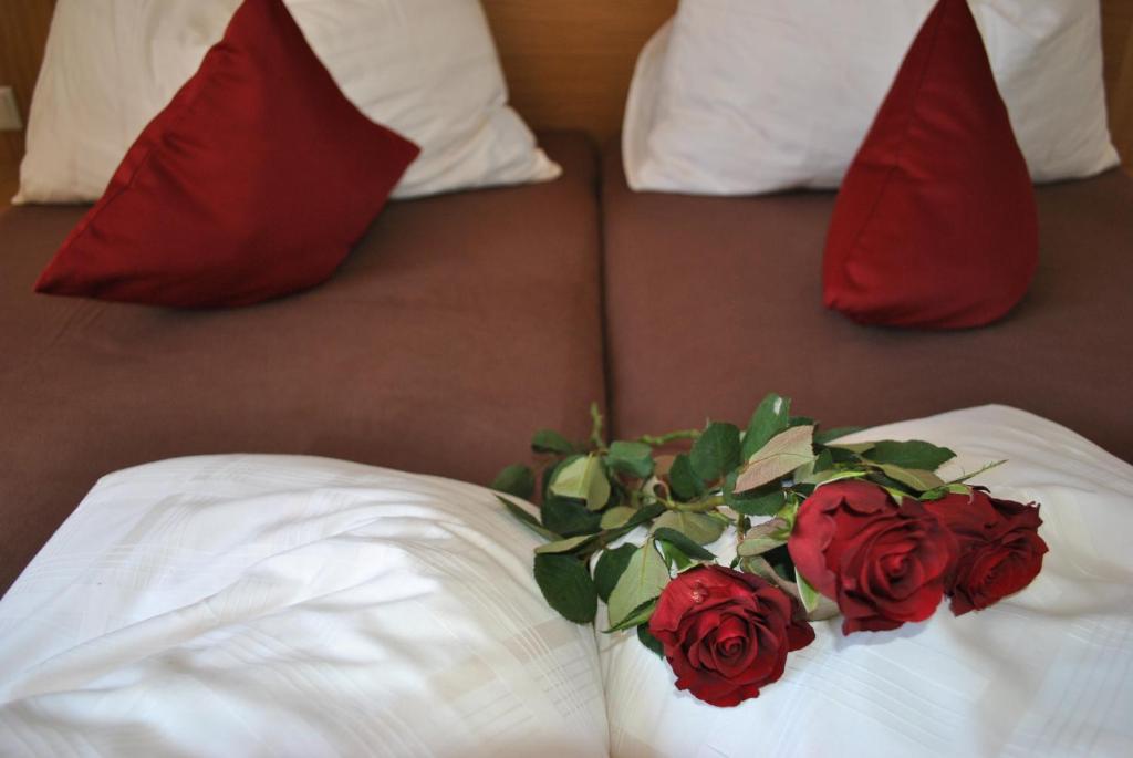 a bouquet of red roses on a bed with pillows at Der Winklhof in Saalfelden am Steinernen Meer