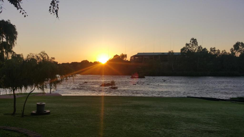 a sunset over a river with the sun setting at Arendsnes in Vanderbijlpark