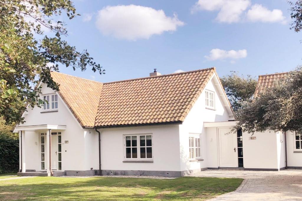 een wit huis met een bruin dak bij B&B Maison Verspyck in Bergen aan Zee