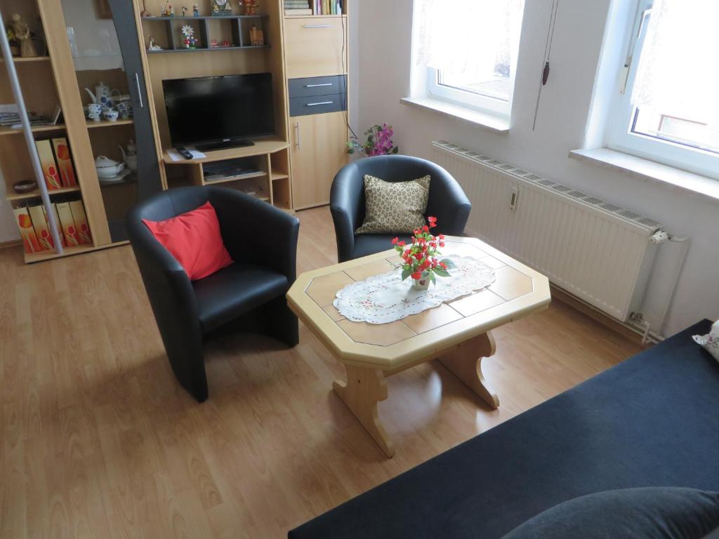 uma sala de estar com duas cadeiras e uma mesa de centro em Ferienwohnung Zahn em Oelsnitz