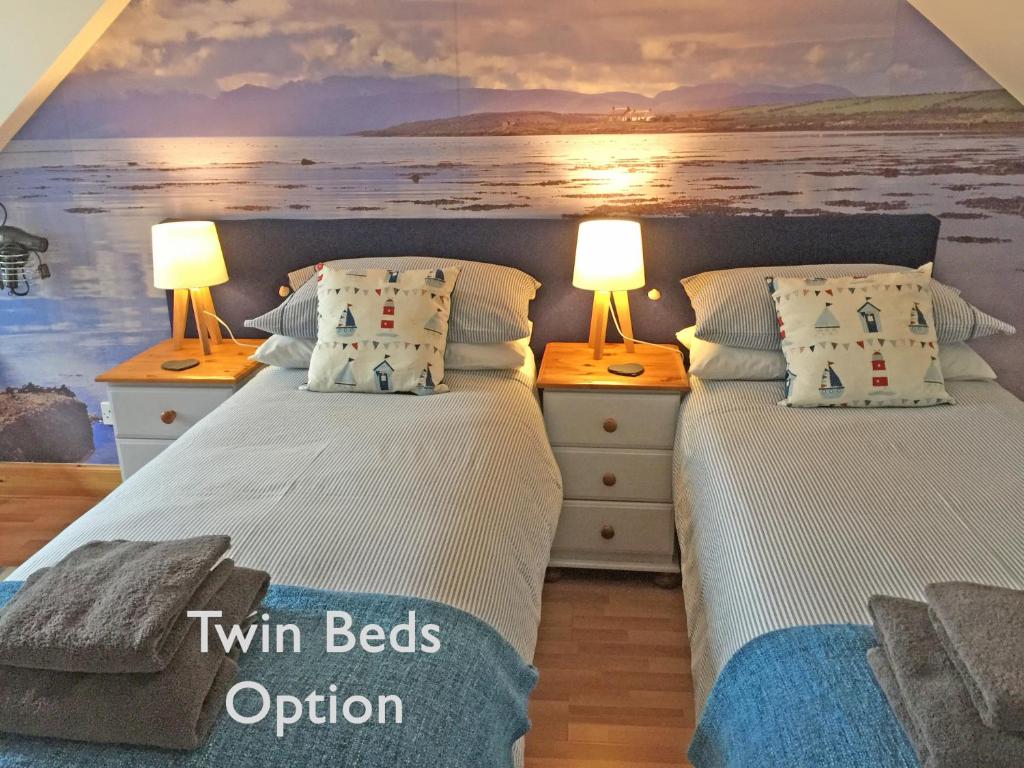 two twin beds in a room with two lamps at Old Fisherman's Cottage in Rothesay