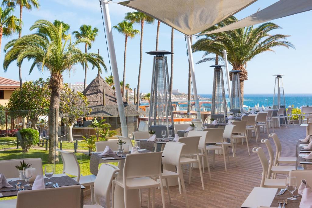 una fila de mesas y sillas en un complejo con palmeras en Iberostar Waves Bouganville Playa, en Adeje