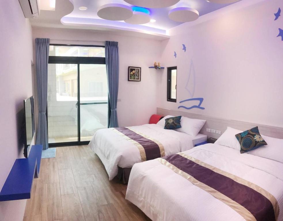 a room with two beds and a window and a tv at Purple Shell Homestay II in Magong