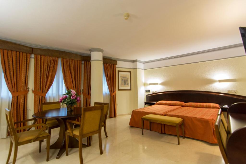 a bedroom with a bed and a table and chairs at Hotel San Antonio in Albacete