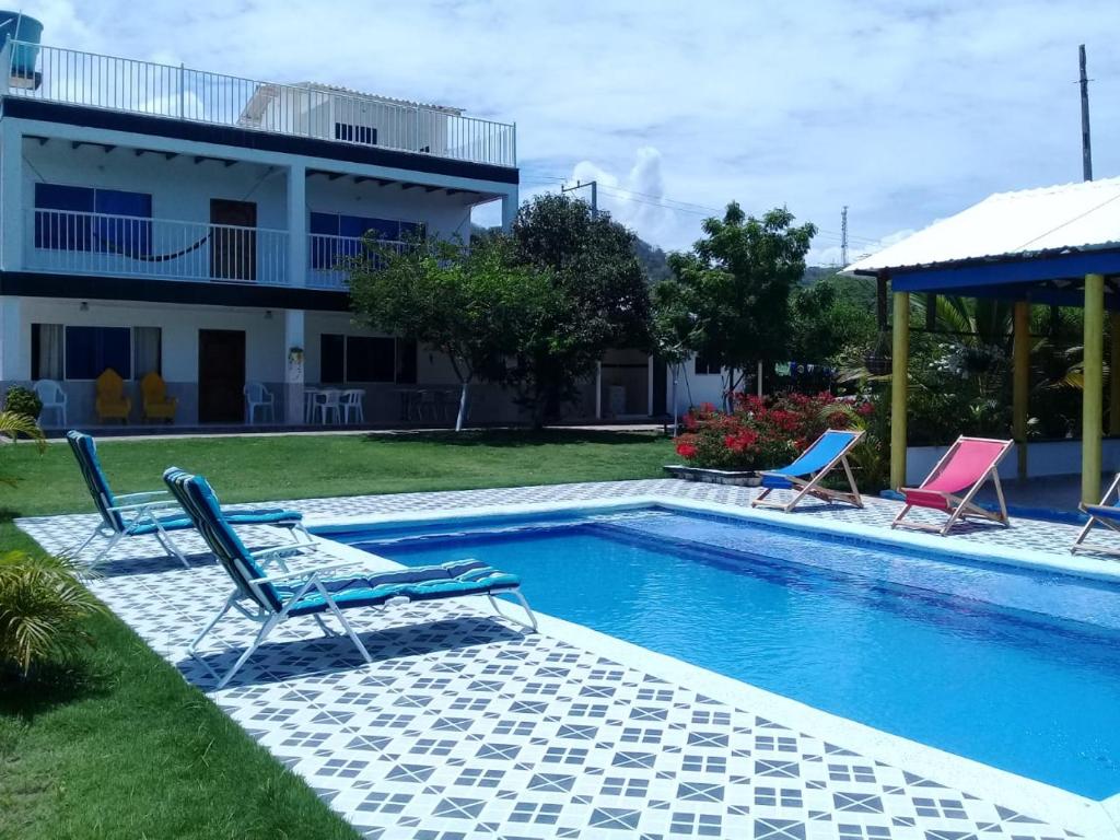 een zwembad met twee stoelen en een huis bij Casa de Campo Palmarito in Tubará