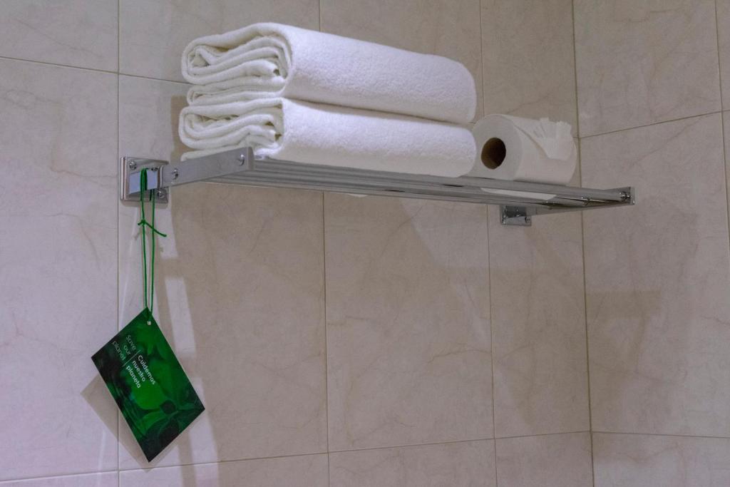 a towel rack with towels and a roll of toilet paper at Hotel Aeropuerto Los Cabos in San José del Cabo