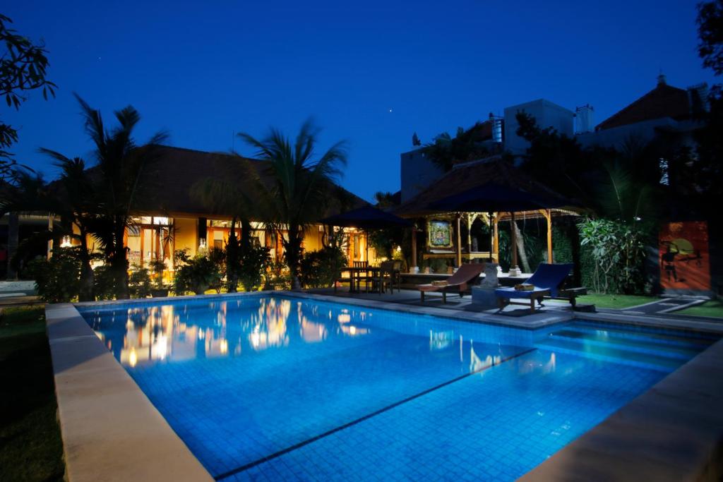 a swimming pool at night with two chairs and a house at Graha Madesimon in Ketewel